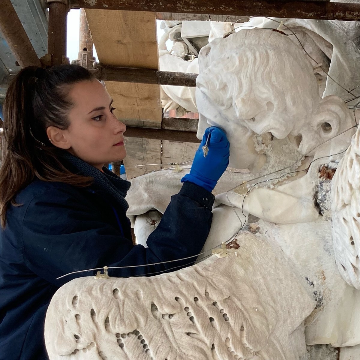 Restauratrice durante un intervento su una scultura in marmo